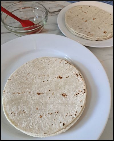 Corn tortillas on two white plates